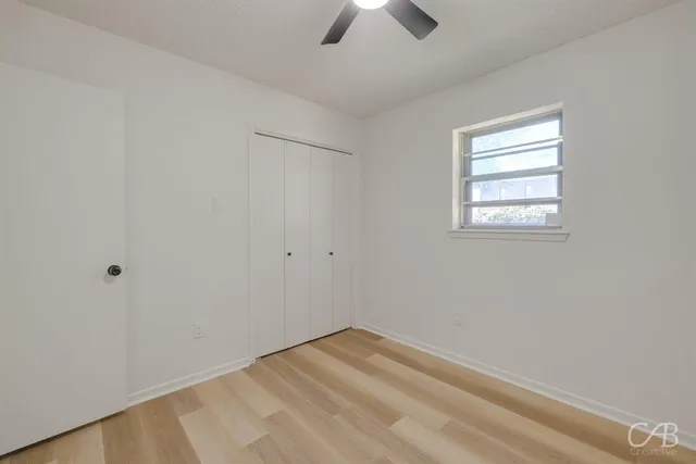 an empty room with a window and a ceiling fan