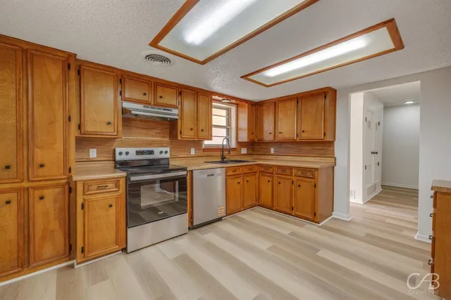 a kitchen with stainless steel appliances granite countertop a stove refrigerator sink and cabinets