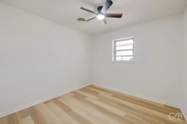an empty room with a window and a fan