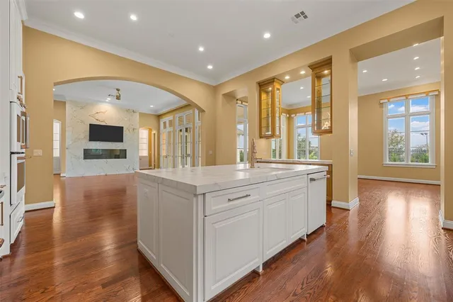 a large white kitchen with a large window a sink and stainless steel appliances
