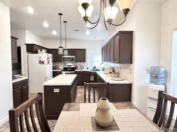 a kitchen with stainless steel appliances granite countertop a sink a stove a refrigerator cabinets and chairs