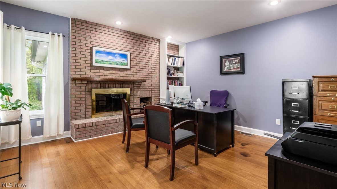 2531 Nicholas Lane Dresden, OH 43821 - Photo 11 of 40 Spacious room featuring wood-finish flooring, a brick fireplace with a brass-colored firebox, built-in shelving, and a large window