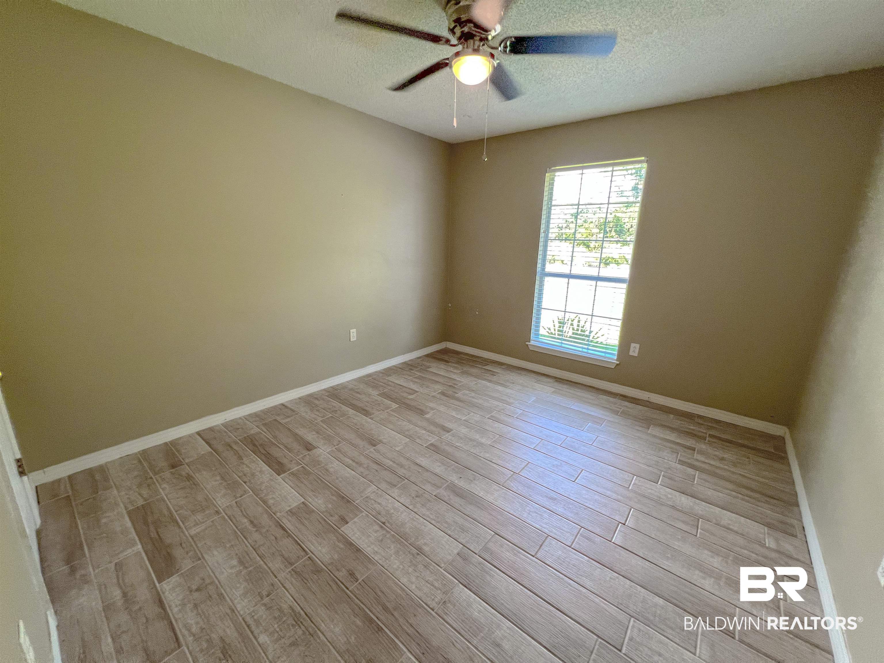 1200 South Juniper Street Foley, AL 36535 - Photo 9 of 23 Unfurnished room with a textured ceiling, light wood-type flooring, and ceiling fan
