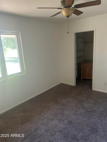 an empty room with a chandelier fan and windows