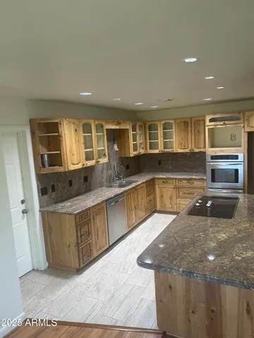 a large kitchen with kitchen island a large counter top and stainless steel appliances