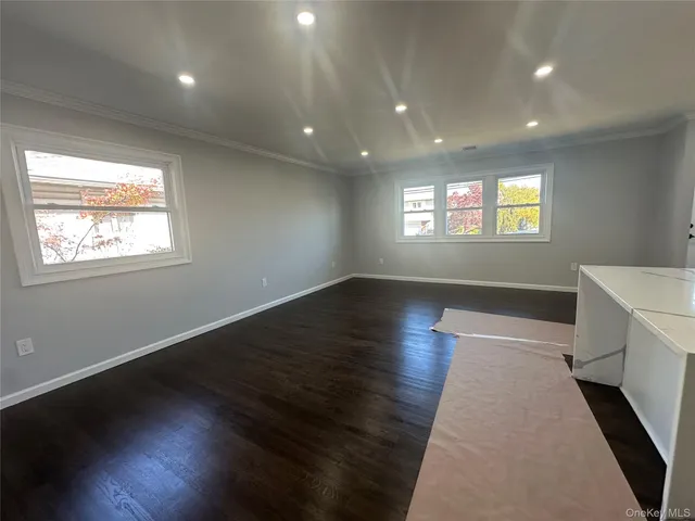an entryway in a hall with wooden floor and a window