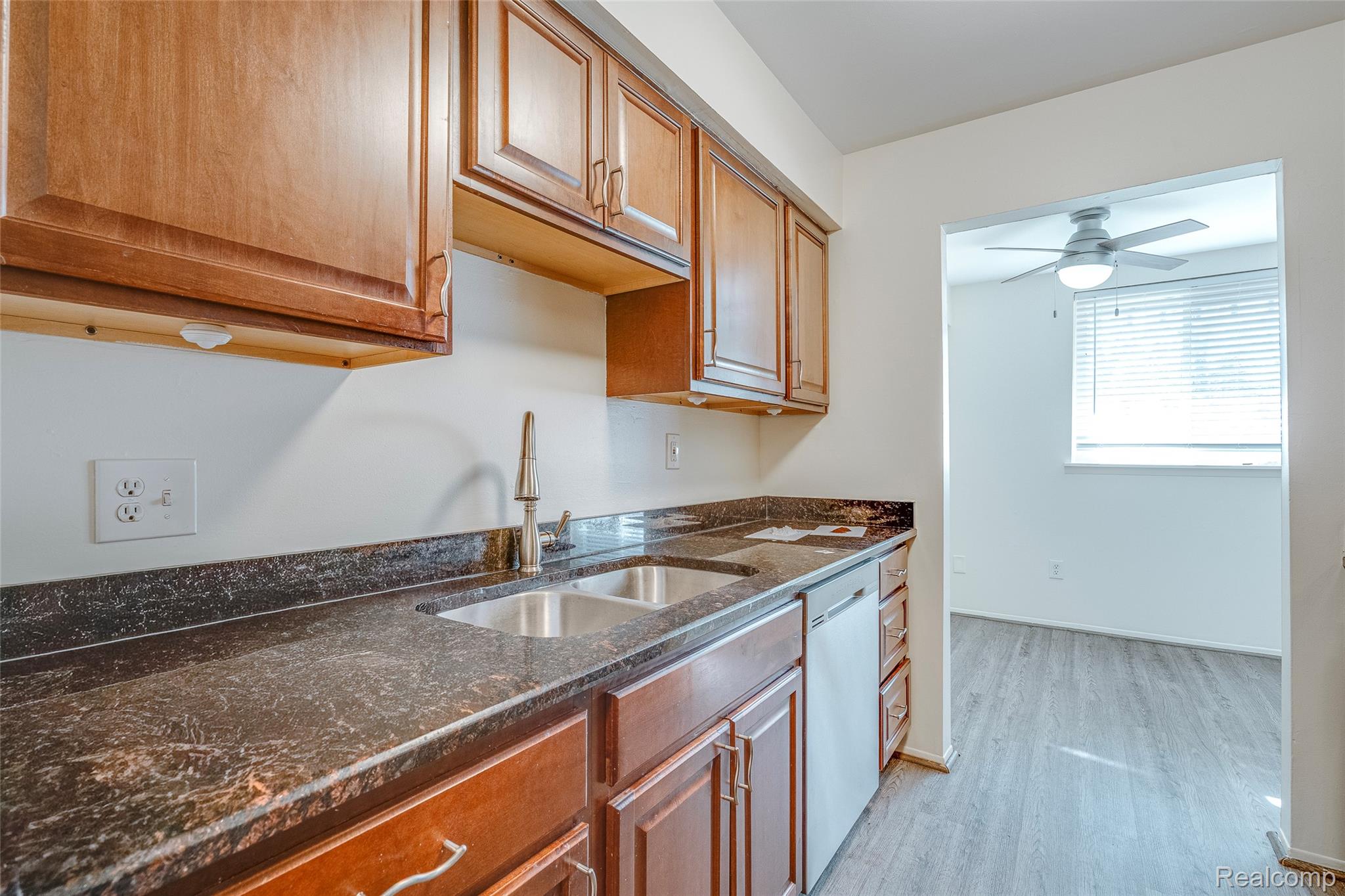 29860 West 12 Mile Road, Unit 604 Farmington, MI 48334 - Photo 5 of 26 Kitchen featuring dark stone counters, light wood finished floors, wood finish cabinets, dishwasher, and a ceiling fan