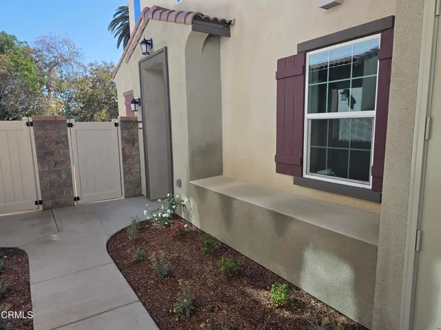a view of a house with a large window and potted plants