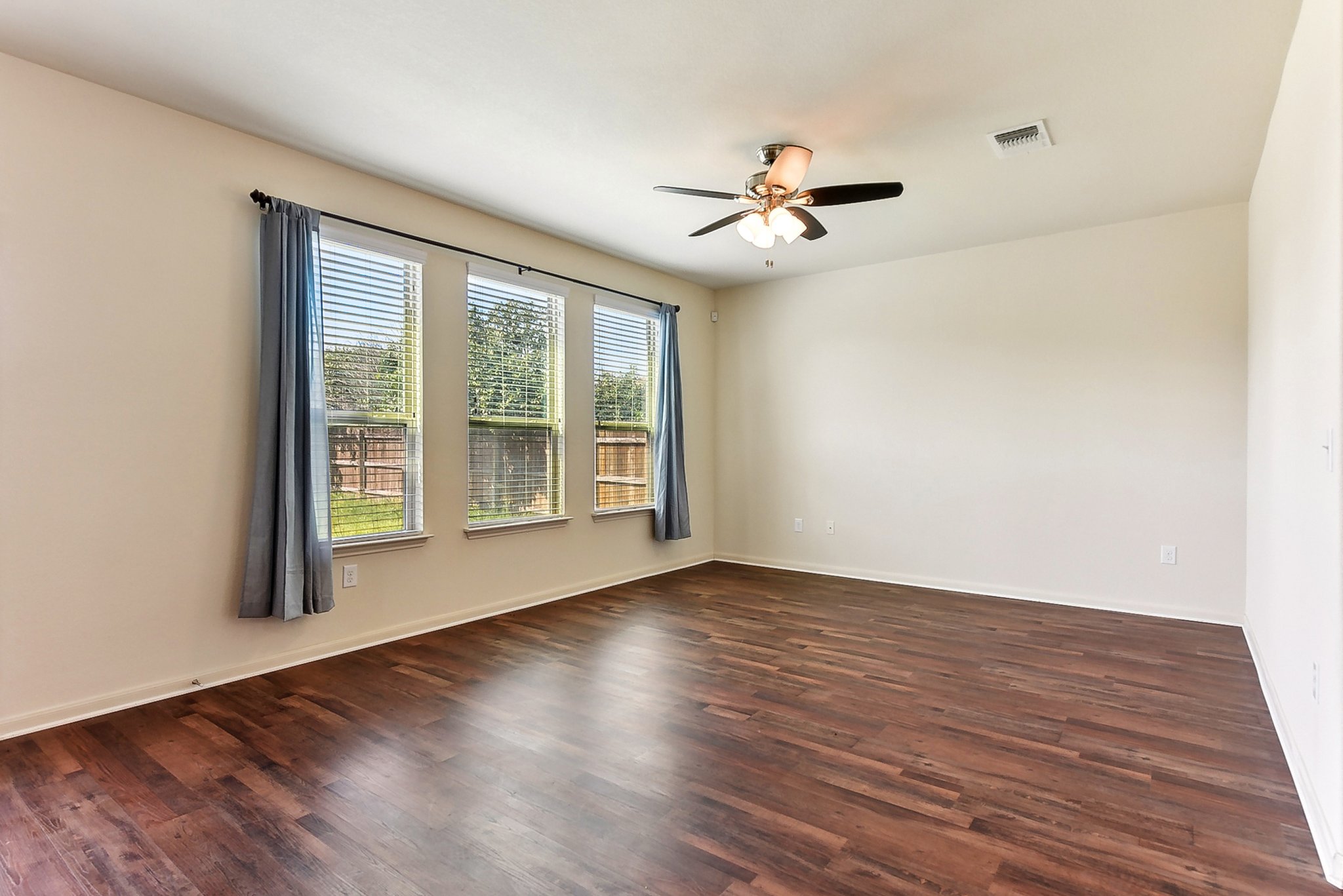 310 Potters Peak Way Georgetown, TX 78626 - Photo 6 of 21 Spacious room featuring wood-finish flooring, three large windows with blinds and drapery, and a ceiling fan with integrated lighting