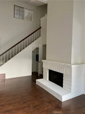 a view of an empty room with wooden floor and a fireplace