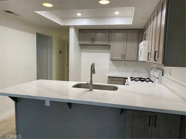 a kitchen with kitchen island a sink a stove and white cabinets