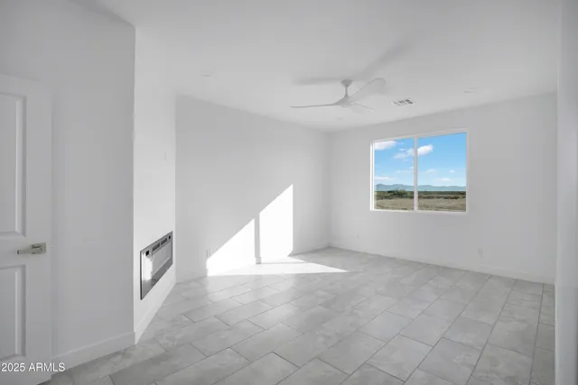 an empty room with windows and chandelier fan