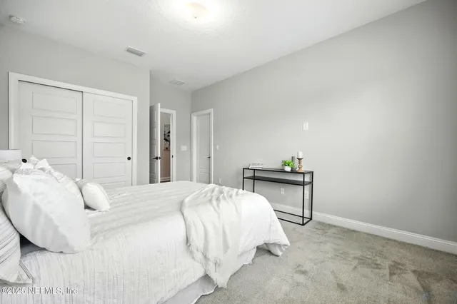 a bedroom with a bed table chair and a window