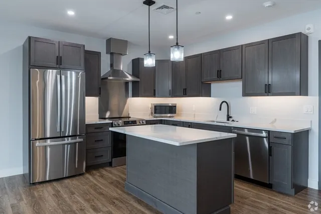 a kitchen with stainless steel appliances granite countertop a refrigerator a sink and a stove