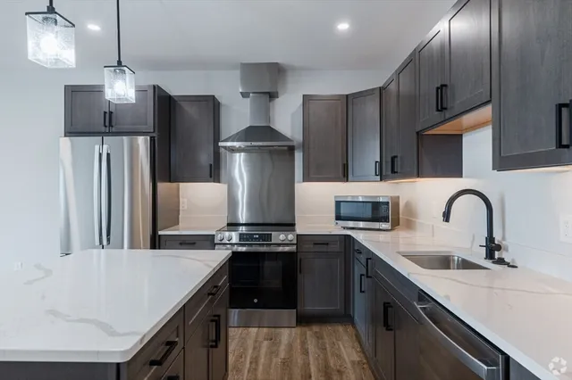 a kitchen with stainless steel appliances a sink a stove a refrigerator and cabinets