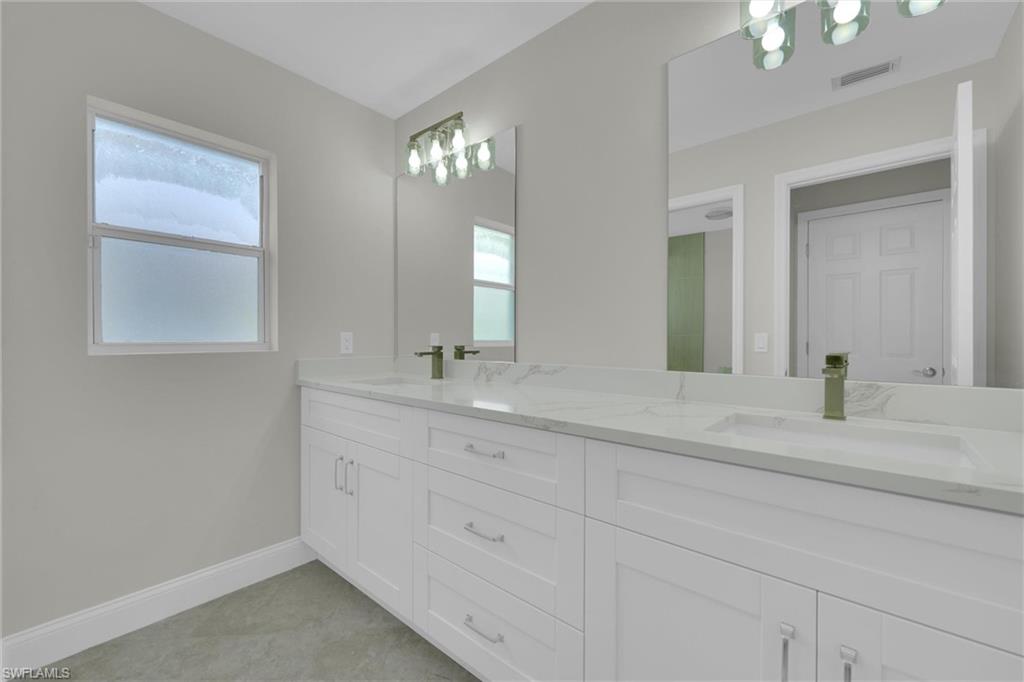 20620 Park Place Estero, FL 33928 - Photo 19 of 28 Full bathroom with a sink, double vanity, baseboards, and visible vents