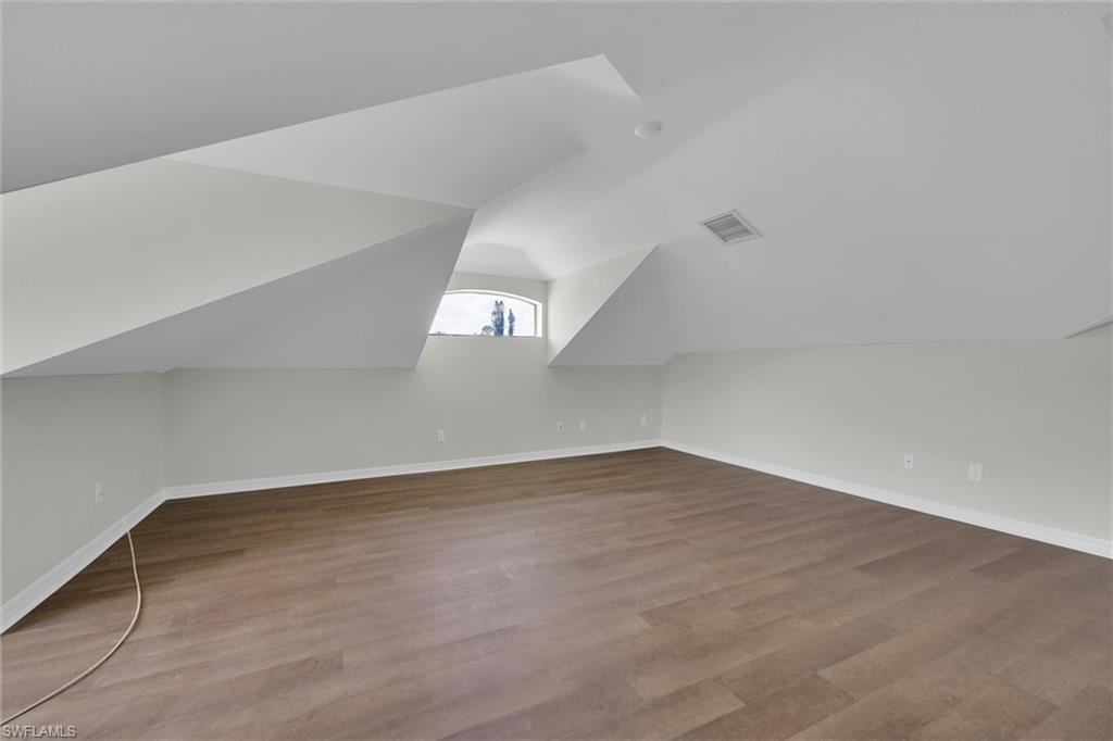 20620 Park Place Estero, FL 33928 - Photo 22 of 28 Additional living space featuring baseboards, vaulted ceiling, wood finished floors, and visible vents