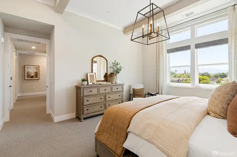a bedroom with a bed a chandelier and dresser