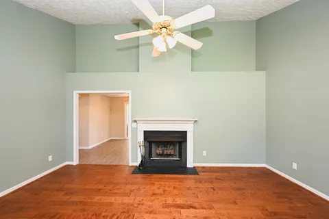 a view of an empty room with chandelier fan and fireplace