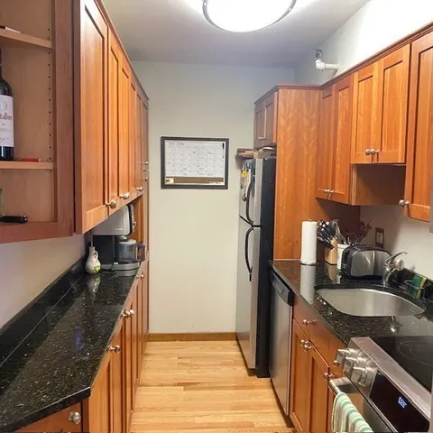 a kitchen with stainless steel appliances granite countertop a refrigerator a stove and a sink with wooden floor