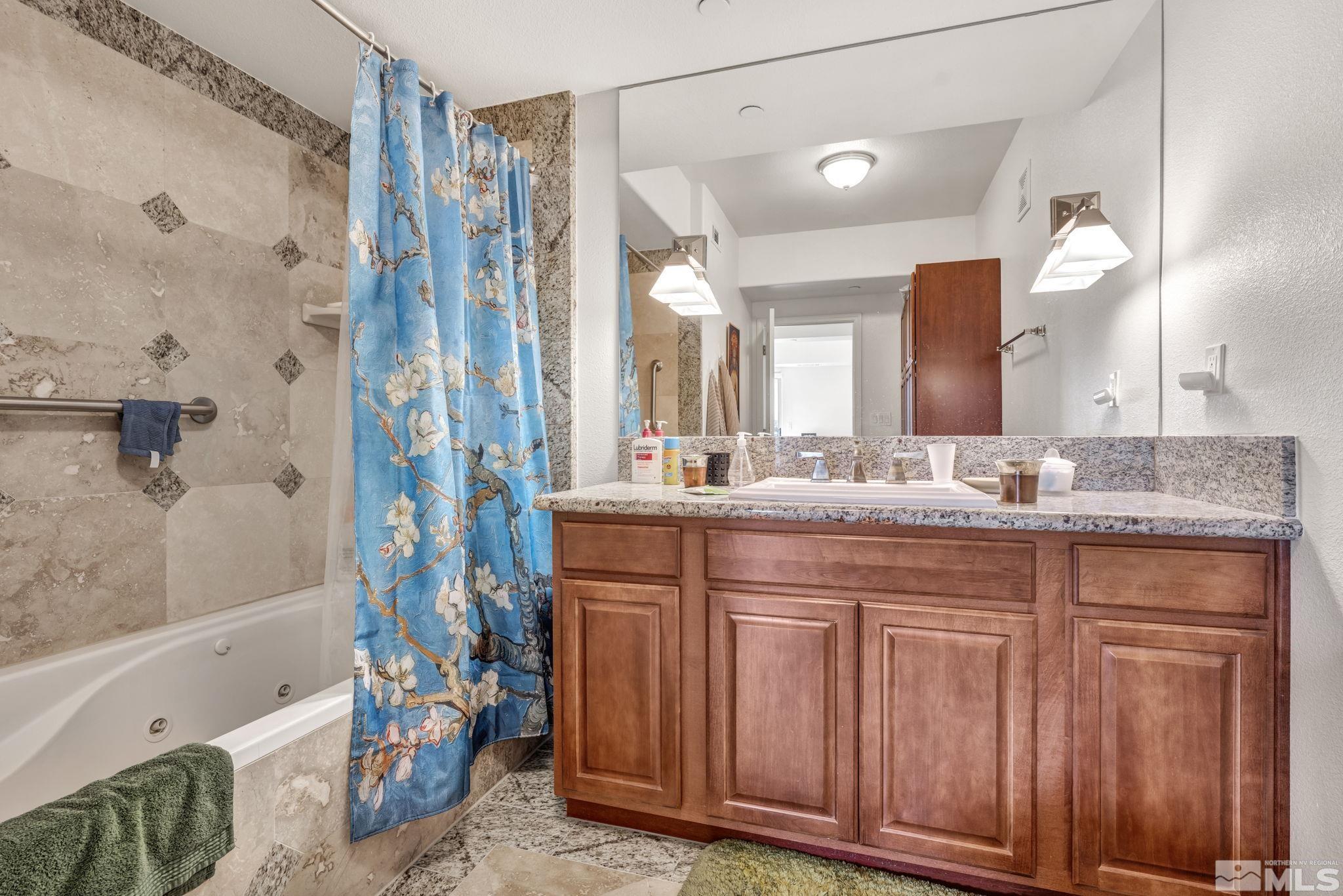 200 West 2nd Street, Unit 1207 Reno, NV 89501 - Photo 12 of 39 a bathroom with a granite countertop sink a mirror a bathtub and shower