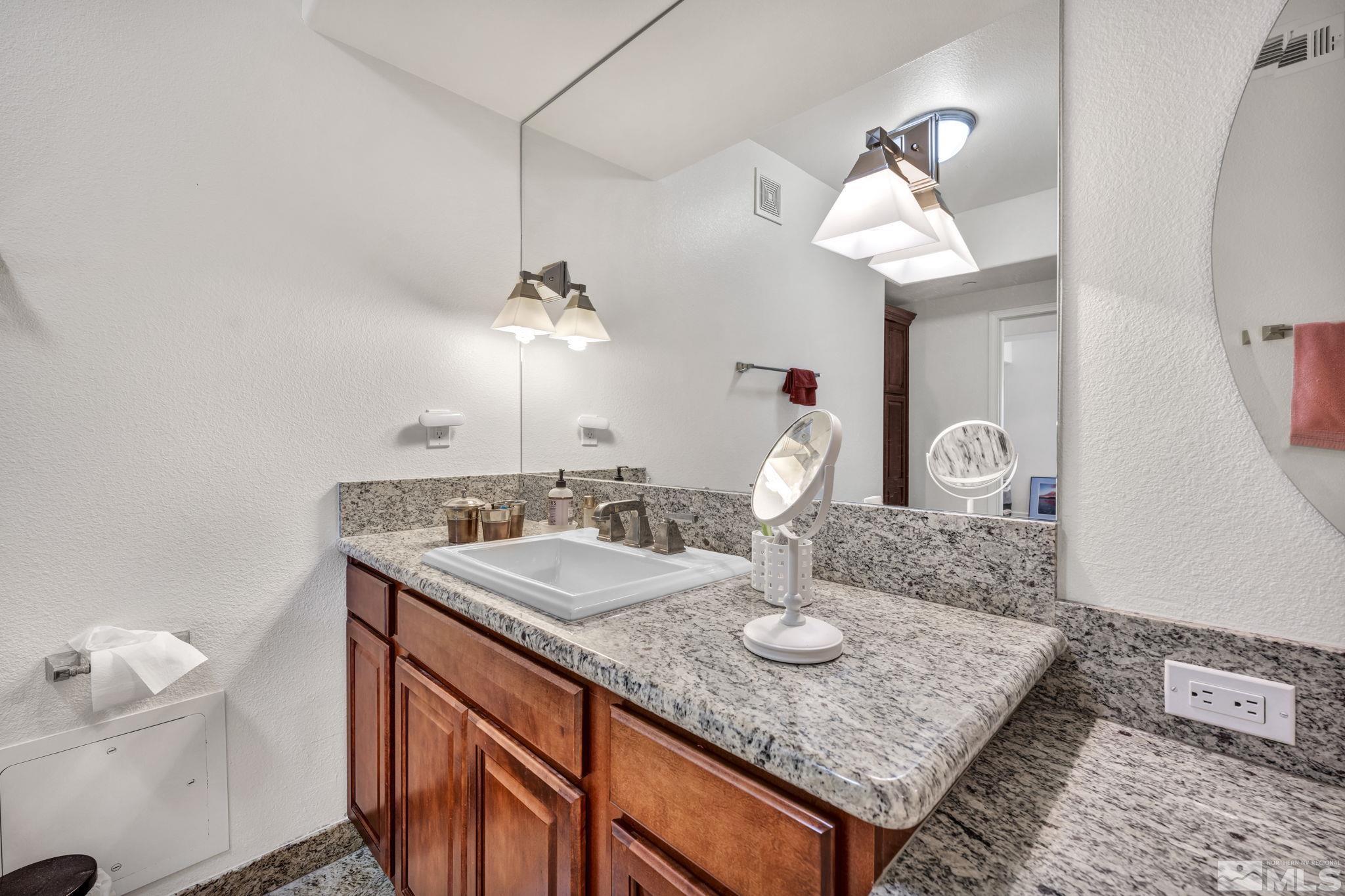 200 West 2nd Street, Unit 1207 Reno, NV 89501 - Photo 21 of 39 a bathroom with a granite countertop sink a toilet and a mirror