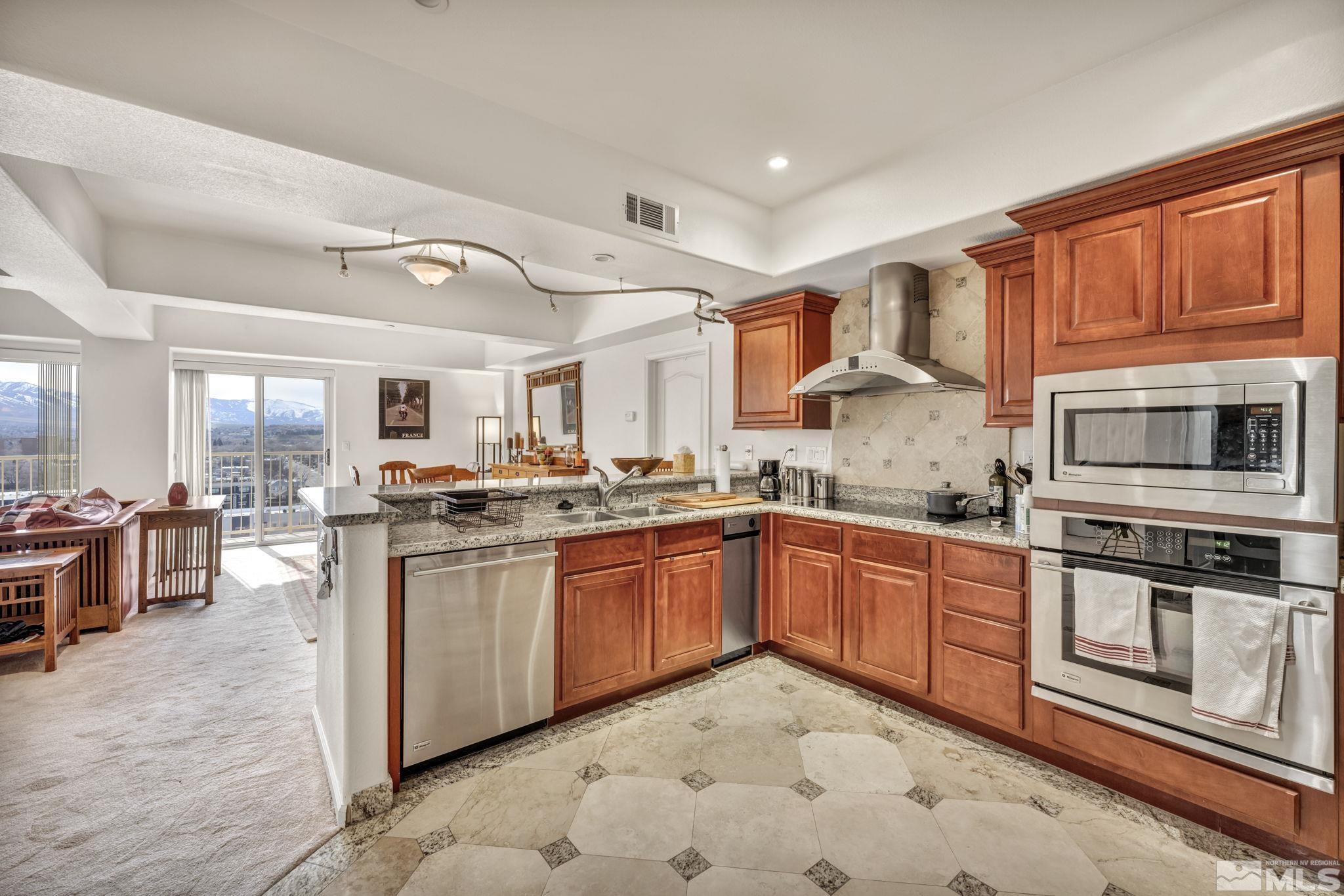 200 West 2nd Street, Unit 1207 Reno, NV 89501 - Photo 28 of 39 a open kitchen with stainless steel appliances granite countertop a stove top oven a sink dishwasher and cabinets with wooden floor