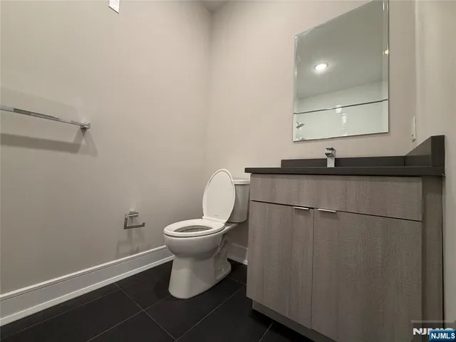 a bathroom with a granite countertop sink toilet and mirror