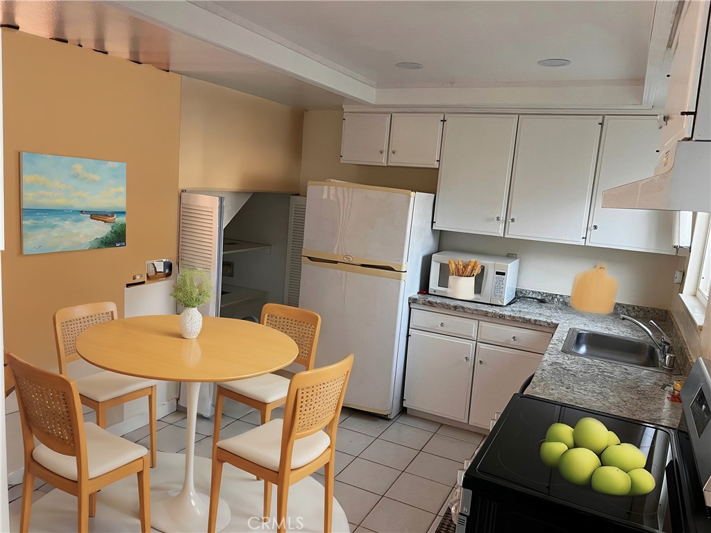 4018 Bryant Court Cypress, CA 90630 - Photo 7 of 16 a kitchen with stainless steel appliances granite countertop a stove a refrigerator white cabinets a dining table and chairs