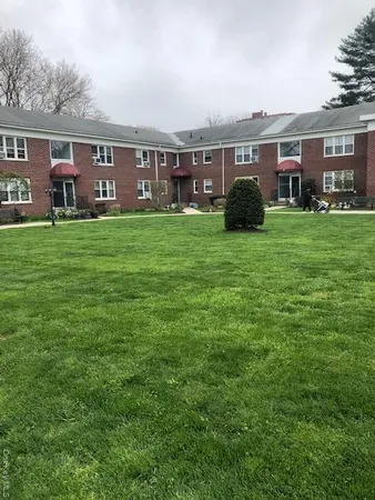 a front view of a house with a garden and trees