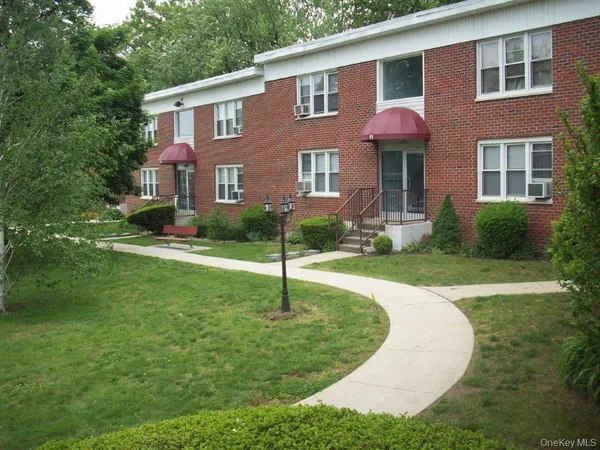 a view of a brick house with a yard patio and a fountain