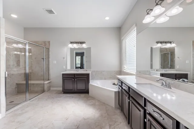 a bathroom with a double vanity sink a toilet a mirror and shower