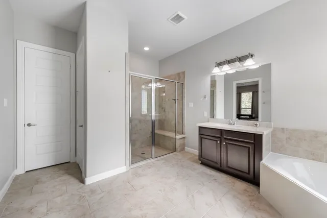 a spacious bathroom with a tub sink and mirror