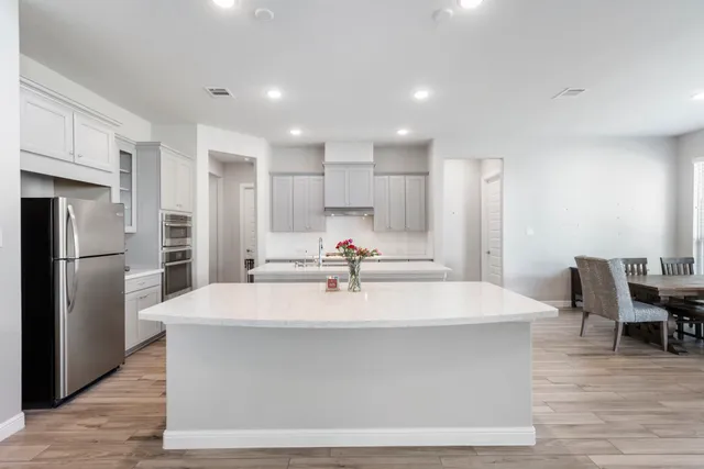 a large kitchen with stainless steel appliances kitchen island a large counter top and a refrigerator