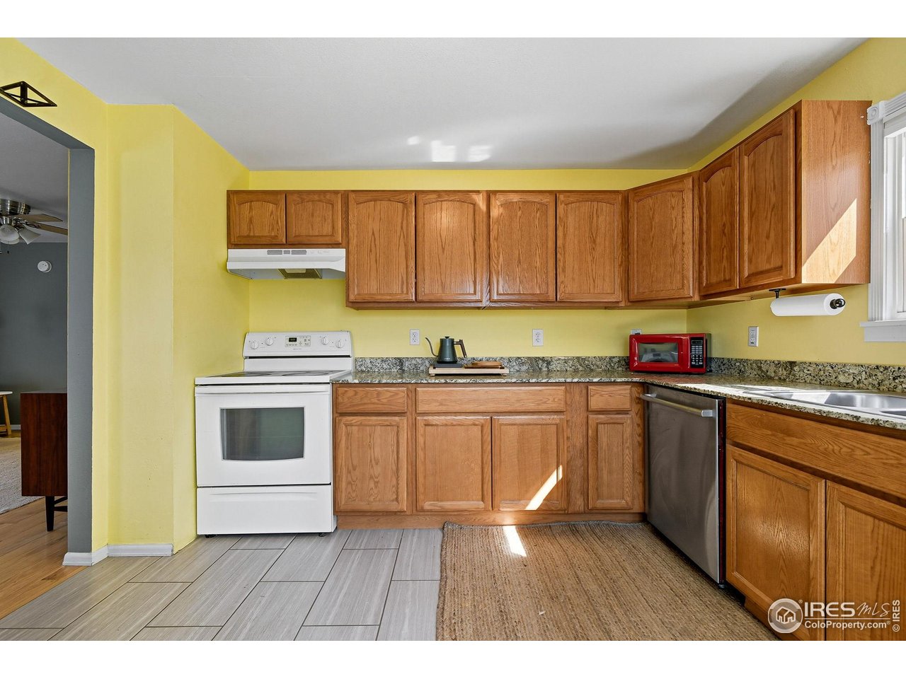 342 4th Avenue Lyons, CO 80540 - Photo 12 of 37 a kitchen with granite countertop a stove a sink dishwasher and a microwave oven with white cabinets