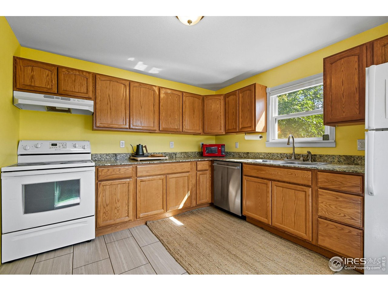 342 4th Avenue Lyons, CO 80540 - Photo 13 of 37 a kitchen with granite countertop wooden cabinets a stove a sink and a microwave