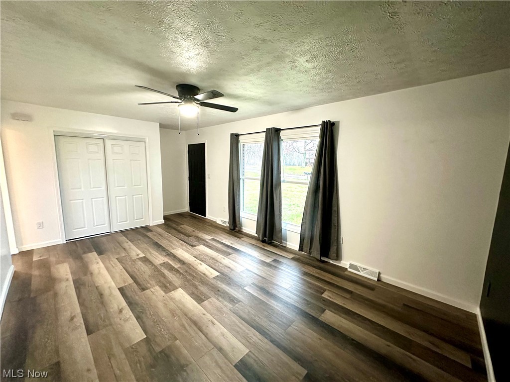 2039 St Johns Road Colliers, WV 26035 - Photo 4 of 35 Unfurnished bedroom featuring dark hardwood / wood-style floors, a closet, a textured ceiling, and ceiling fan