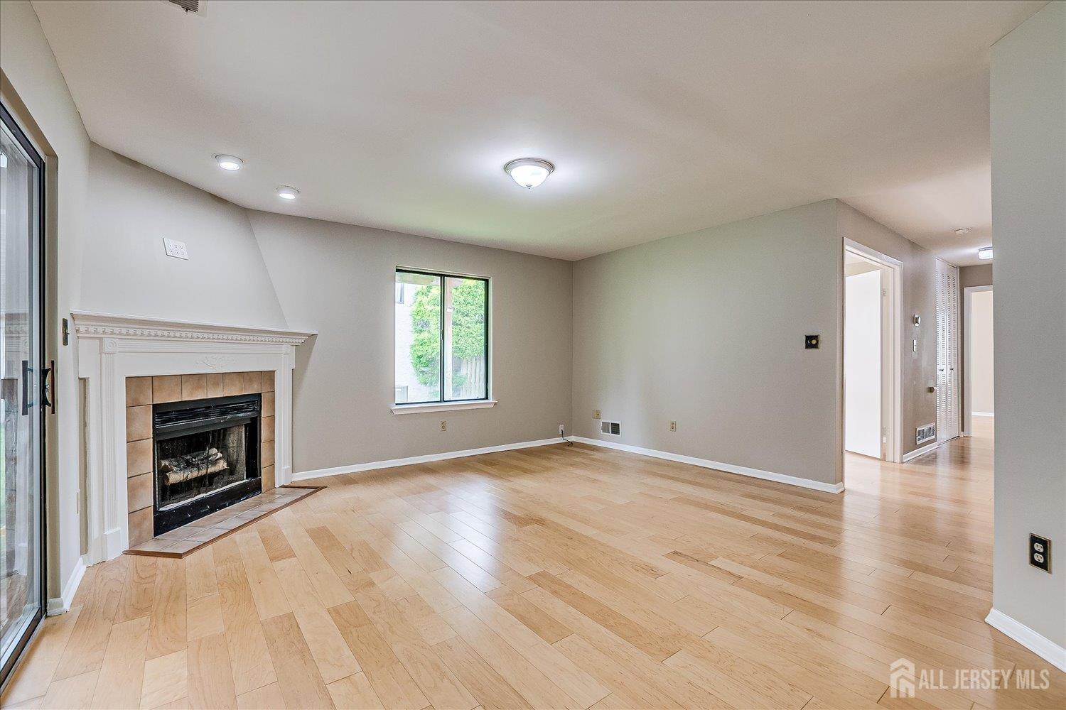 83 Park Gate Drive Edison, NJ 08820 - Photo 19 of 35 an empty room with wooden floor a fireplace and windows
