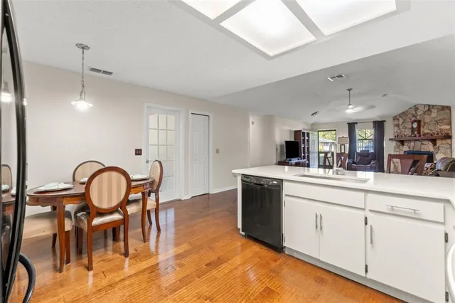a kitchen with stainless steel appliances granite countertop a stove a sink and a dining table with white cabinets