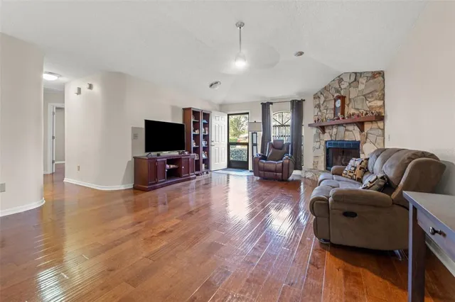 a living room with fireplace furniture flat screen tv and wooden floor