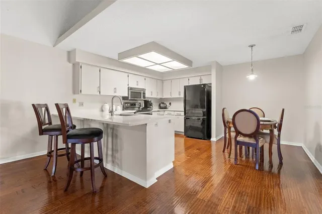 a kitchen with stainless steel appliances granite countertop a dining table chairs refrigerator and microwave