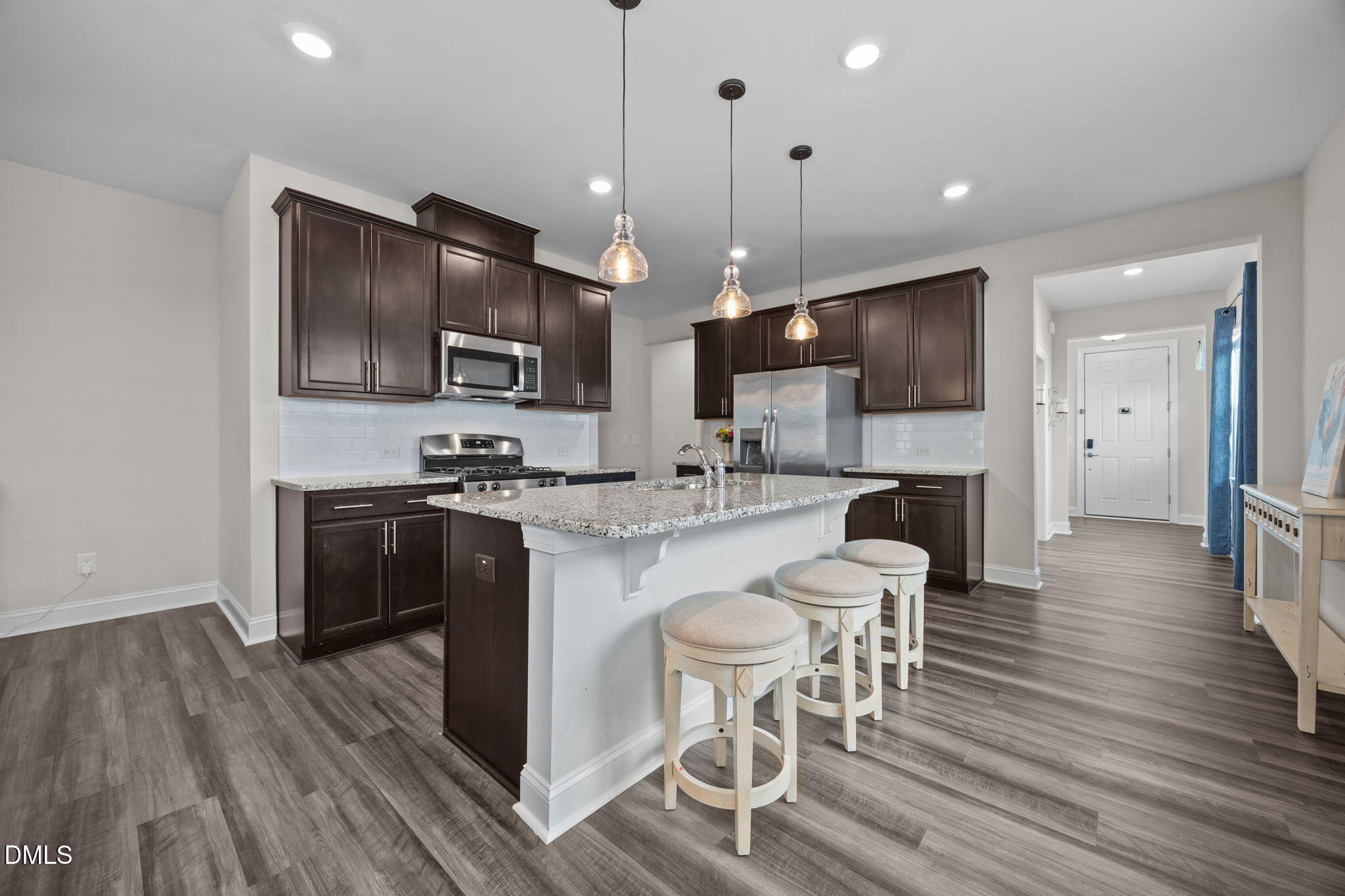 162 Desert Sand Lane Raleigh, NC 27610 - Photo 9 of 33 a kitchen with stainless steel appliances kitchen island granite countertop a stove a sink a refrigerator and a dining table with wooden floor