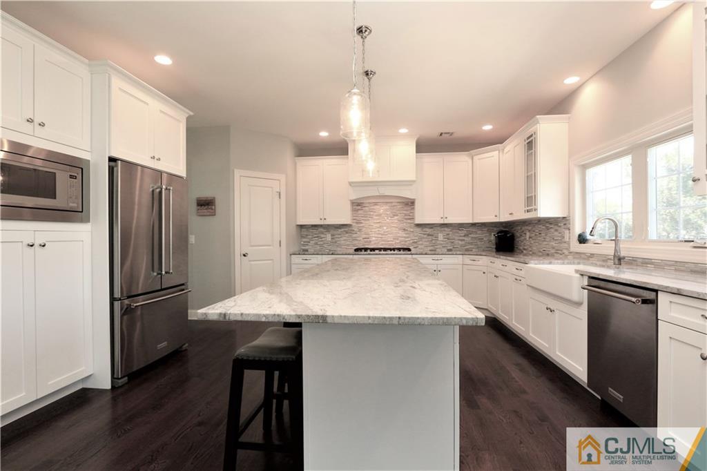 17 Thompson Grove Road Freehold, NJ 07728 - Photo 3 of 25 a kitchen with stainless steel appliances kitchen island granite countertop a refrigerator a sink dishwasher a stove and white cabinets with wooden floor