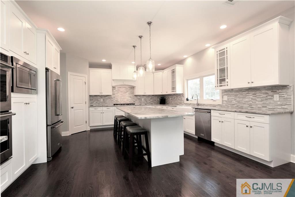 17 Thompson Grove Road Freehold, NJ 07728 - Photo 4 of 25 a kitchen with stainless steel appliances granite countertop a sink a stove a refrigerator and island with wooden floor