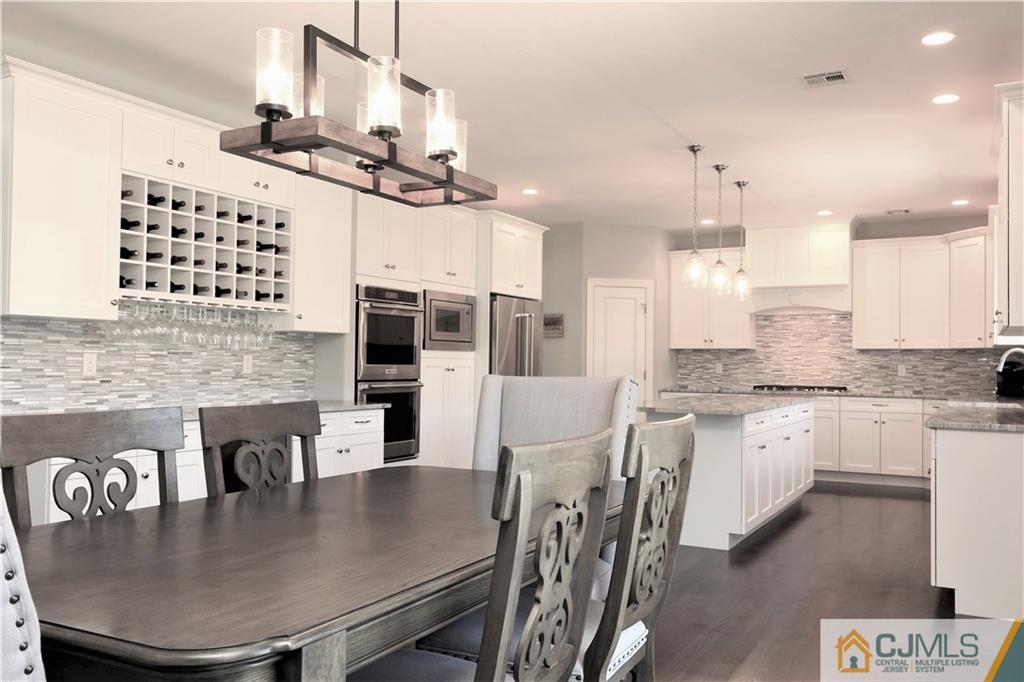 17 Thompson Grove Road Freehold, NJ 07728 - Photo 5 of 25 a kitchen with kitchen island granite countertop a stove a sink a dining table and chairs