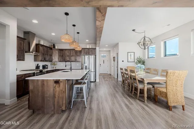 a kitchen with stainless steel appliances a dining table chairs and wooden floor