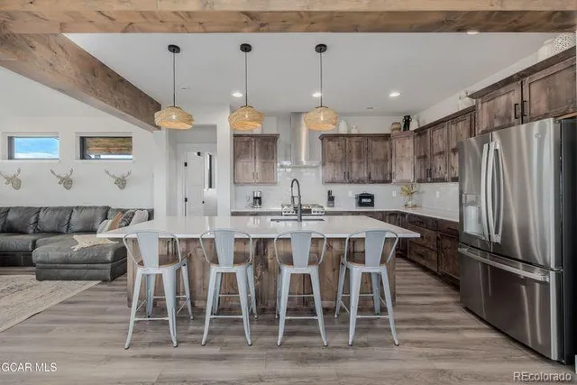 a kitchen with stainless steel appliances granite countertop a table chairs sink and cabinets