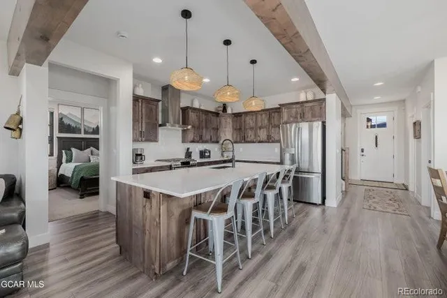 a kitchen with stainless steel appliances a dining table chairs and wooden floor