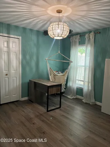 a view of a room with wooden floor a chandelier