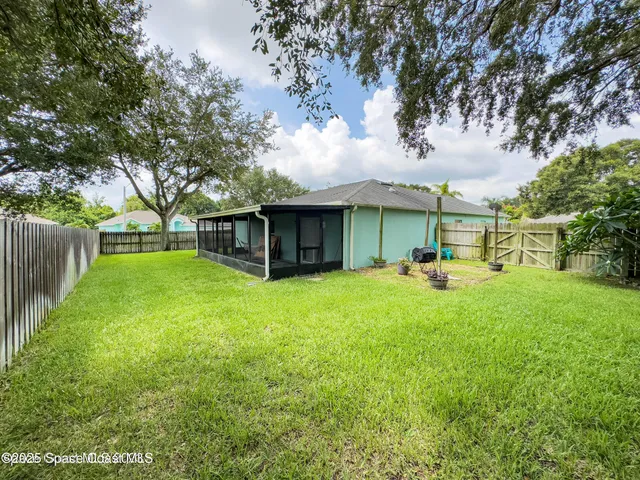 a view of a house with backyard and a tree